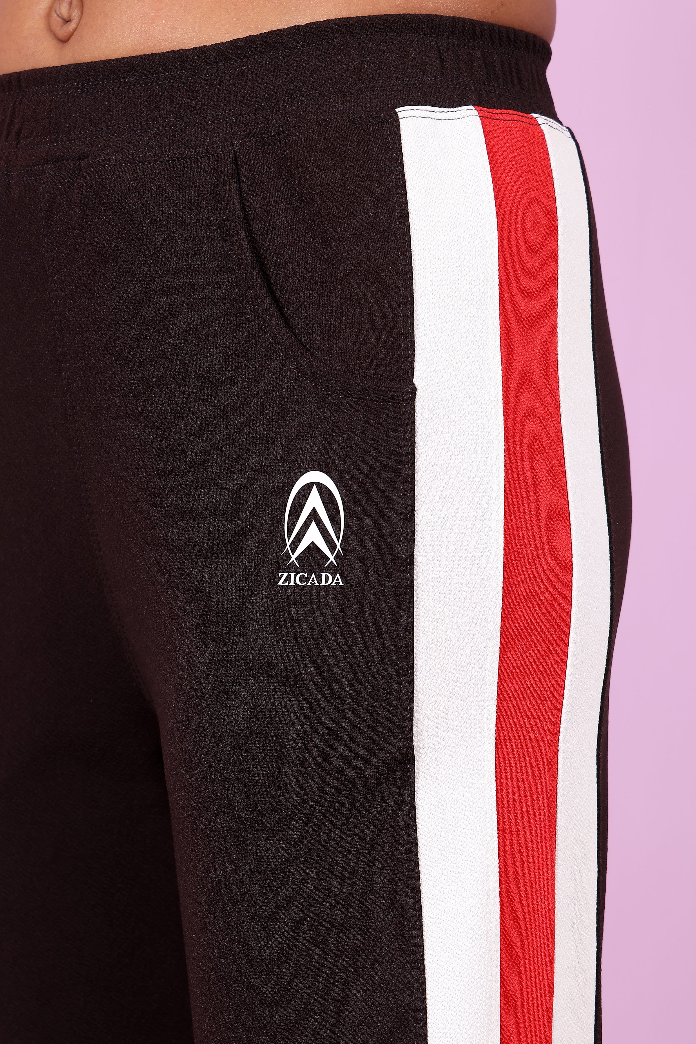 Zicada Black pants with red and white stripes featuring a logo on a light purple background