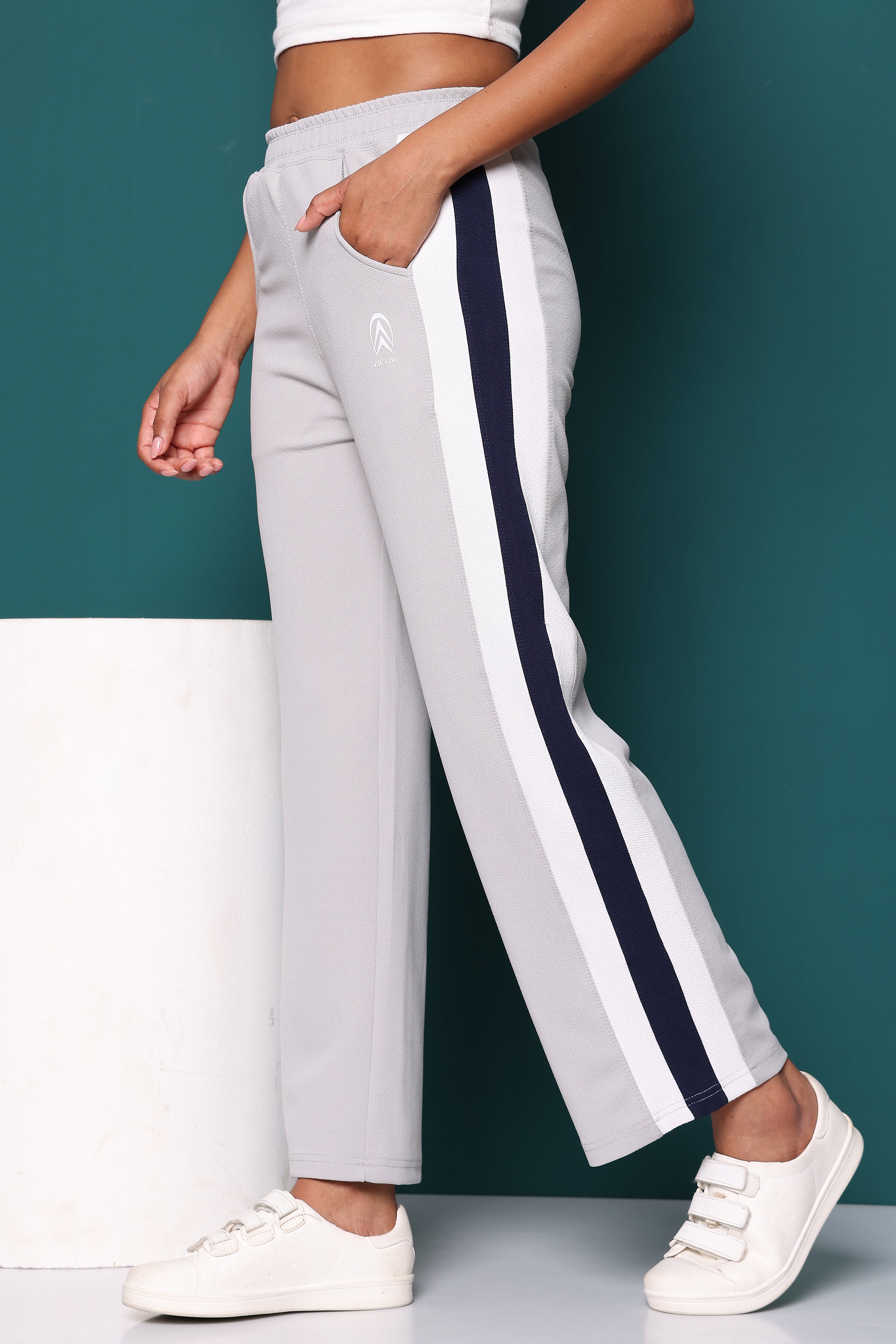 Zicada Gray track pants with navy stripes worn by a person against a teal background