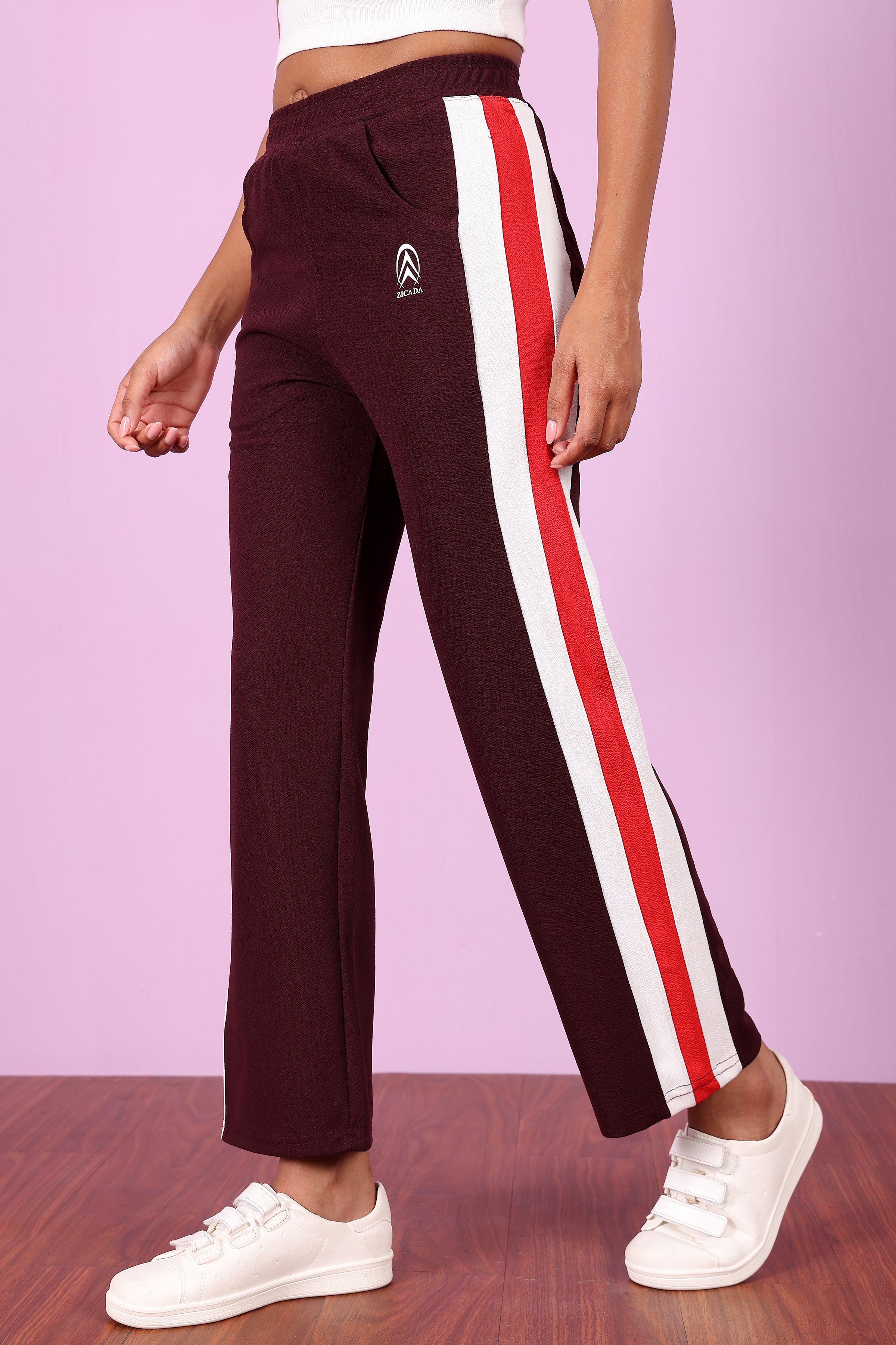 Zicada Maroon track pants with red and white stripes worn by a person on a pink background