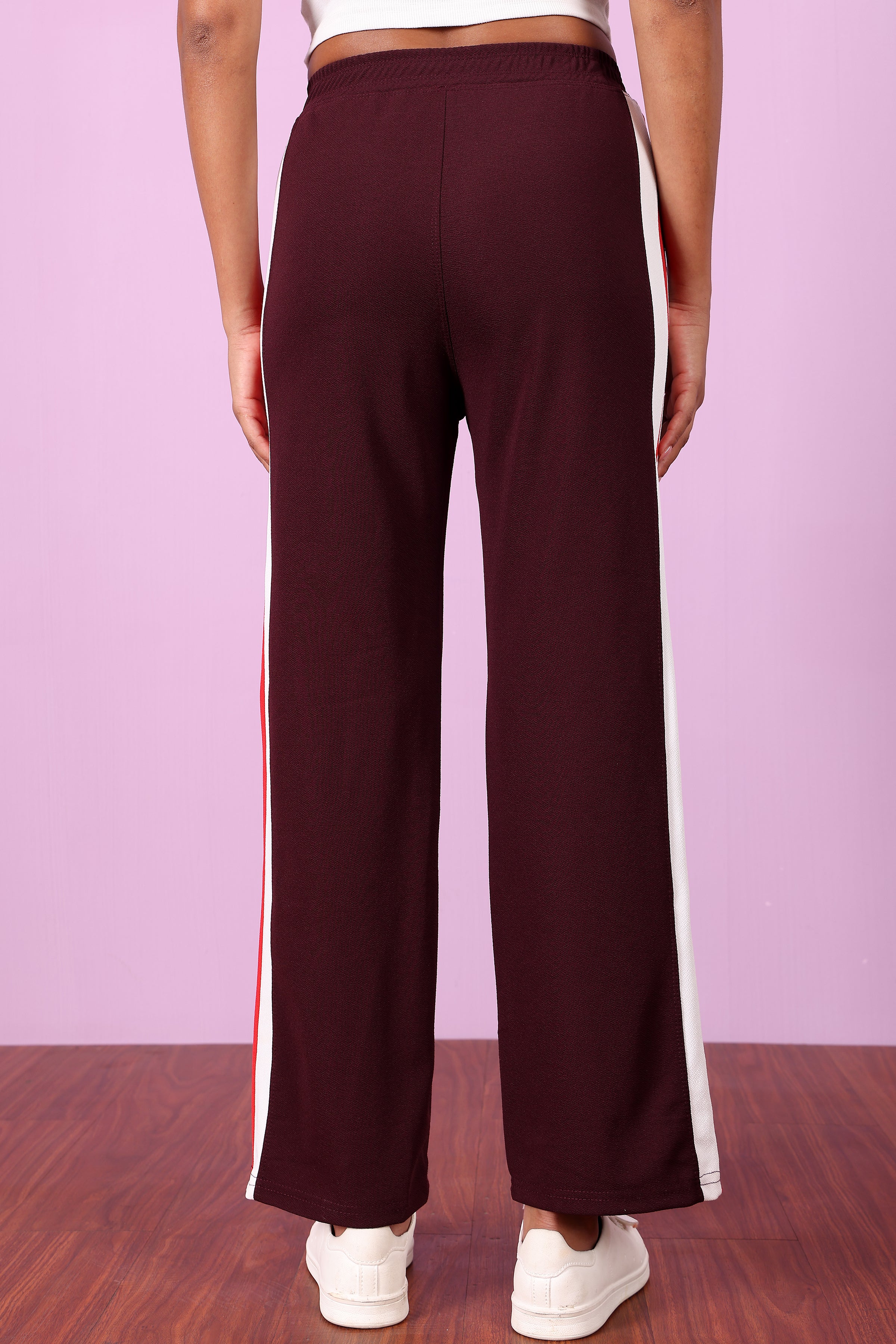 Zicada's Maroon pants with white stripes on a wooden floor and light Purple wall background